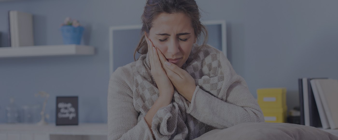 Woman in need of emergency dentistry holding her cheek